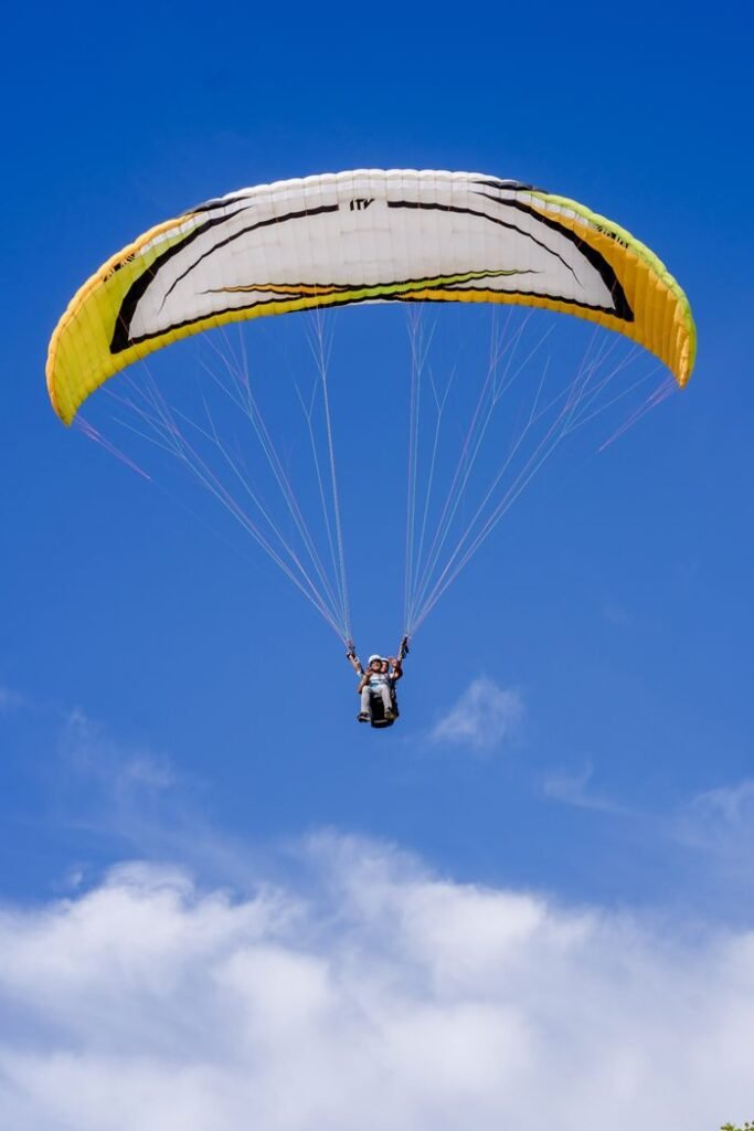 A paraglider enjoying the thrill of flight against a clear blue sky, evoking freedom and adventure.