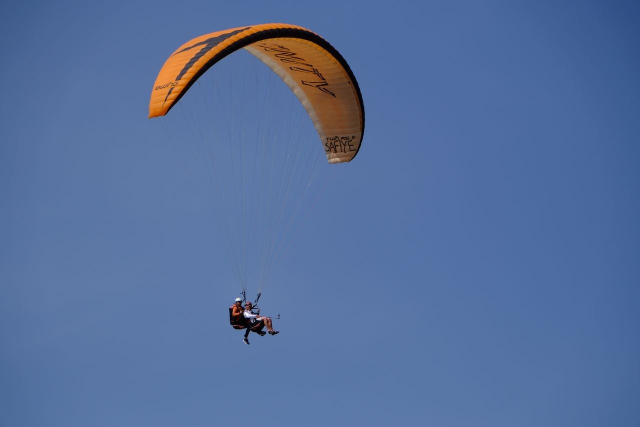 Tandem paragliding flight over Ölüdeniz with clear blue skies.